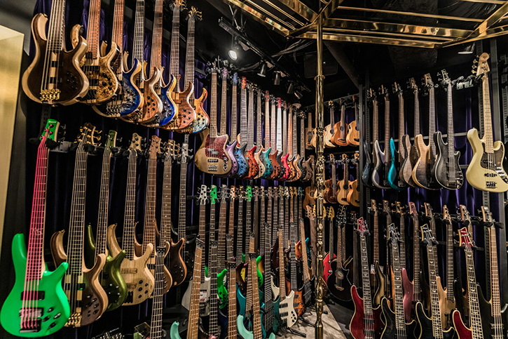 Image of the inside of a music store with loads of bass guitars hanging on the wall